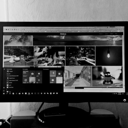 A black and white photo of a computer monitor displaying various images and applications in an indoor setting.