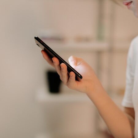 Close-up of a person using a smartphone indoors, focusing on hand and device.