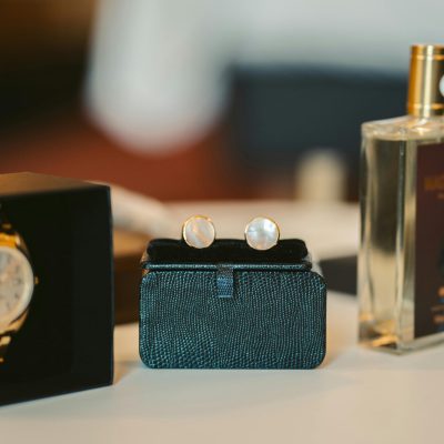 Sophisticated men's watch and cufflinks displayed on a table alongside a bottle of perfume.
